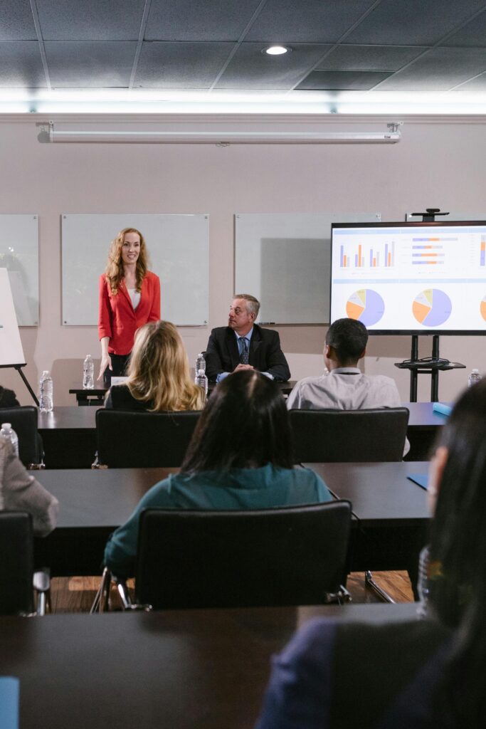 A diverse group of professionals attending a conference presentation with charts displayed.